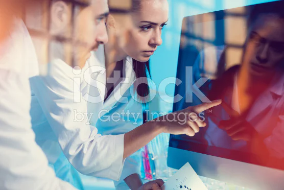 Stock photo of three people in lab coats staring intently at a blank computer monitor