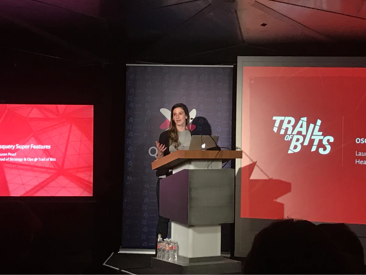 Lauren Pearl presenting Osquery Super Features at QueryCon 2018, with the Trail of Bits logo displayed on the screen behind her